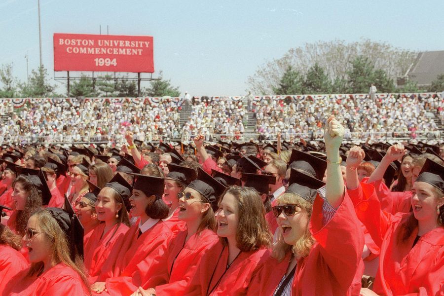 Photo: A large sea of Boston University graduates wearing red gowns and black mortarboards cheer at the 1994 Commencement on Nickerson Field.