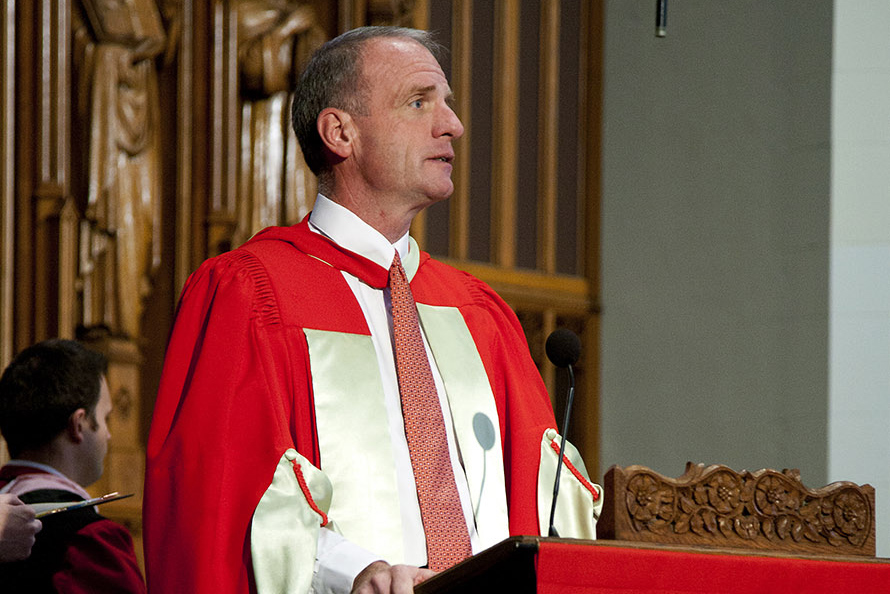 Photo: Robert Allan Hill, dean of Marsh Chapel, wearing a red and gold ceremonial outfit as he speaks at a podium for the 2010 Baccalaureate service.