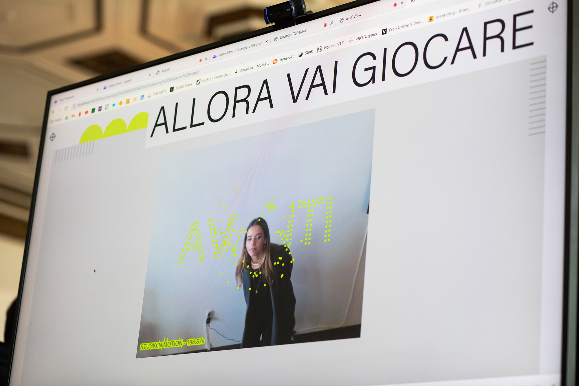 Photo: Andreina De La Blanca (CFA’23) demonstrates one of the “mini experiences,” or interactive games, she created for her graphic design thesis. A screen is shows a webpage with a photo of a person bending down and interacting with floating neon text.