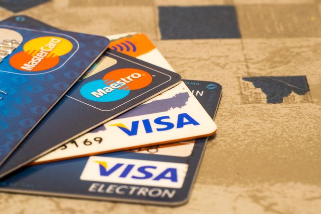 Photo: A pile of four credit cards, two from MasterCard and two from VISA, on a table.