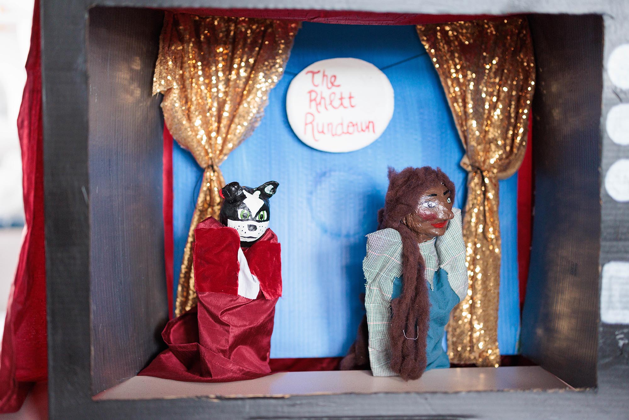 Photo: A paper constructed stage with puppets, one representing the BU mascot, a terrier on the left. And another representing a Black woman with a blue outfit on the right.