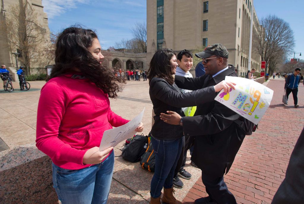 Ken Elmore, seen at right in a baseball cap, hugs a line of students, left, who hold signs along Comm Ave near Marsh Plaza, after the Boston marathon bombing. In the photo, Elmore and a young woman are about to hug.
