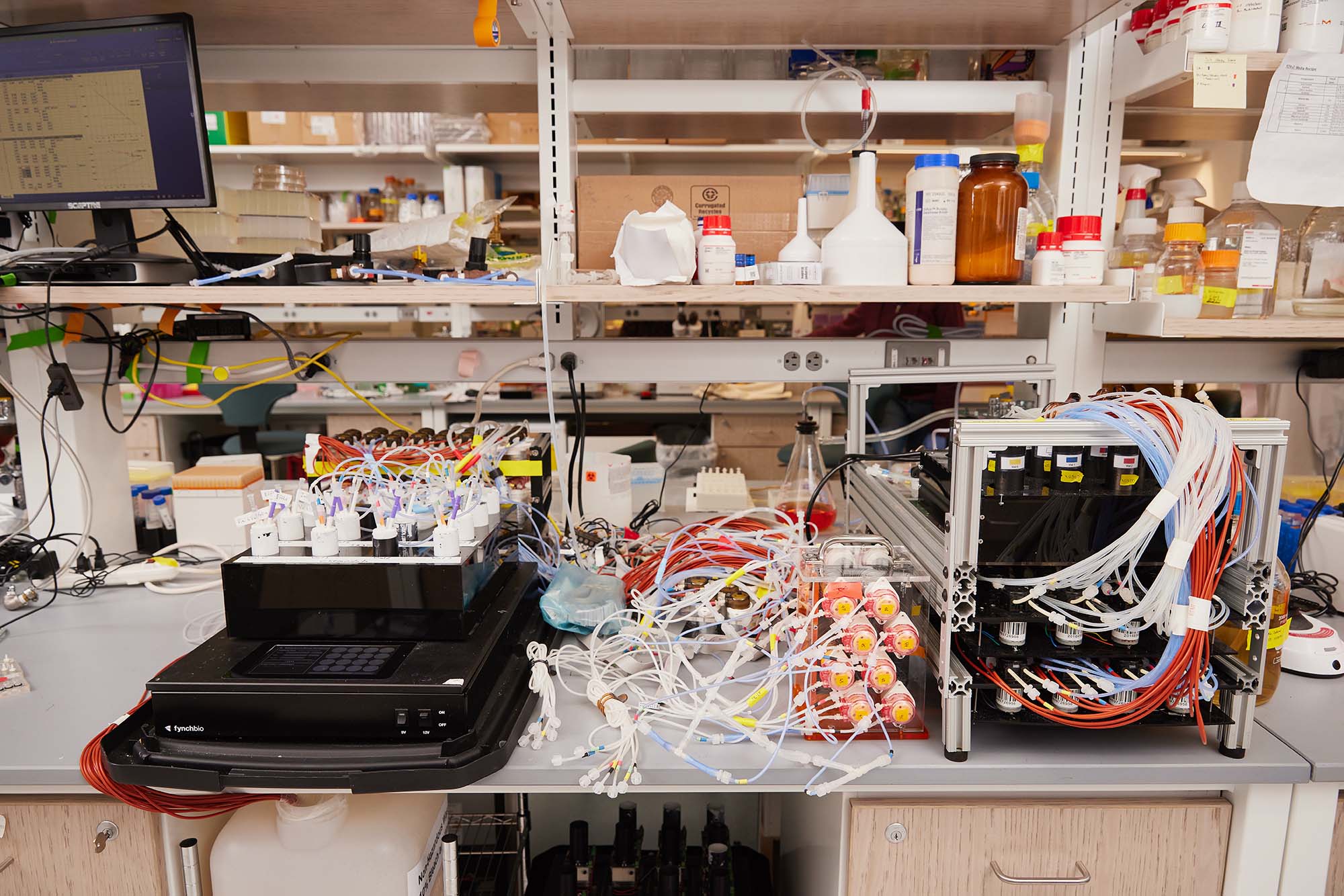 Photo: Wide view of the electronics lab featuring machinery, wires, and test tubes to be used in the machine.