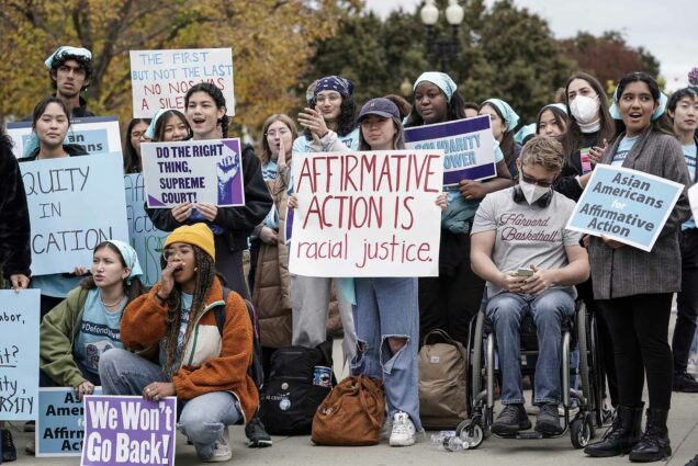 Photo: Activists demonstrate in front of the the Supreme Court. A group of diverse young people hold signs i favor of Affirmative action and chant as they stand outside.