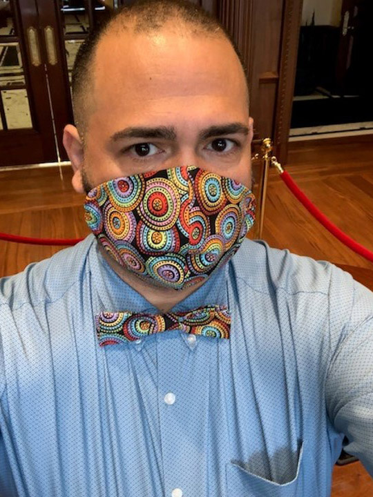 Photo of Jesus Nater with a matching mask and bowtie that is brown with a colorful swirl pattern.