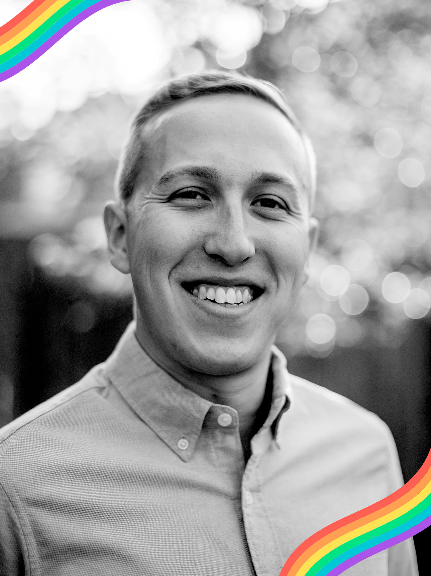 Black and white headshot of Ethan Sobel (COM’13) smiling in a light colored button down shirt with the background blurred.