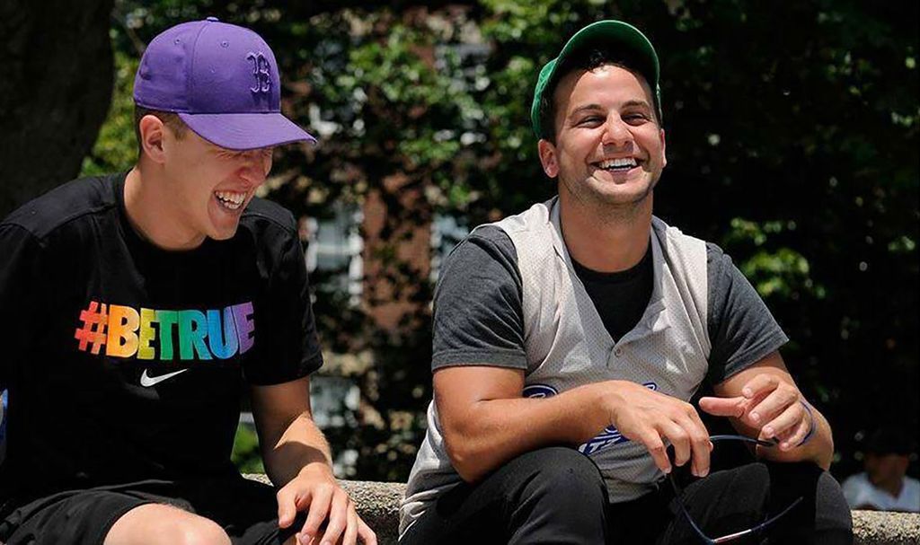 Photo of Sobel and a friend at a Pride event in 2013, after Sobel came out. Sobel wears a purple Boston Red Sox hat as he and his friend laugh.