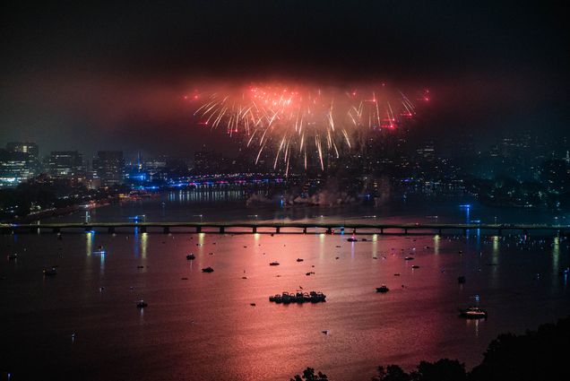 Photo: 4th of July fireworks are shown going off on a dark night above the Charles river. Red and orange fireworks light up the night sky and show the Boston skyline.