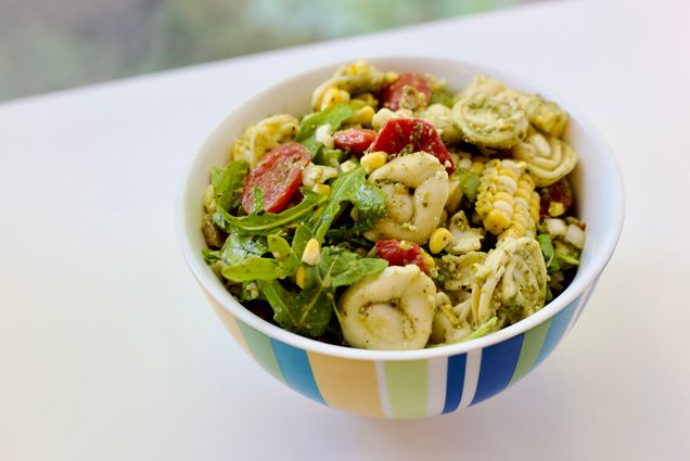 Photo: A colorful bowl of tortellini salad on a white countertop.