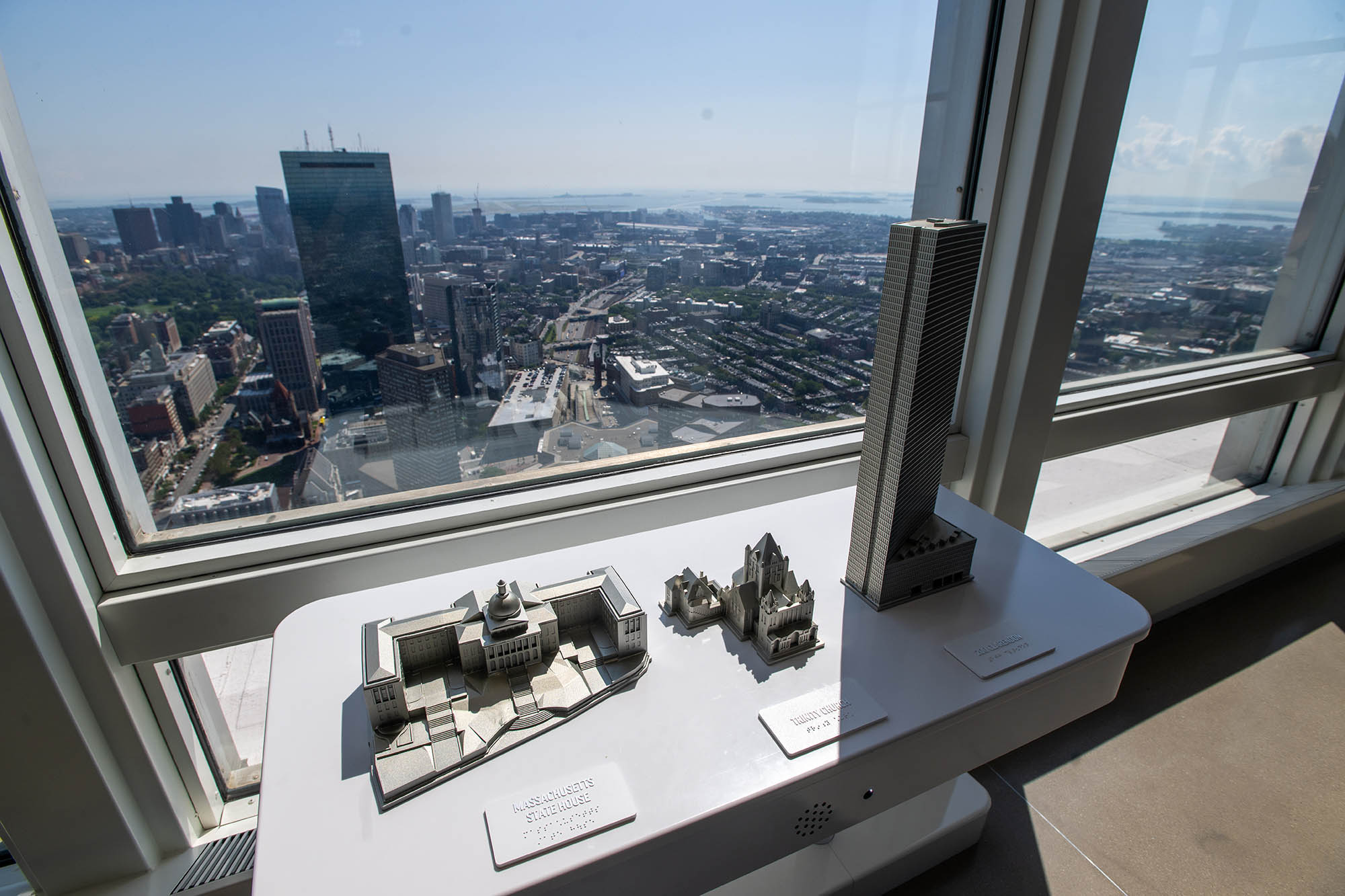 Photo: Small models of the Massachusetts Sate House, Trinity Church, and 200 Clarendon are shown on a table in front of a large window.