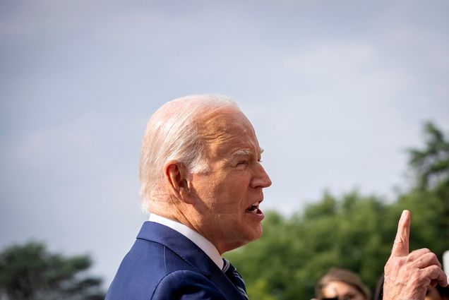 Photo: President Joe Biden, an older white man with white hair and wearing a white collared shirt and blue blazer, is shown from the side. The sleep mark of a CPAP machine can be seen on his cheek.