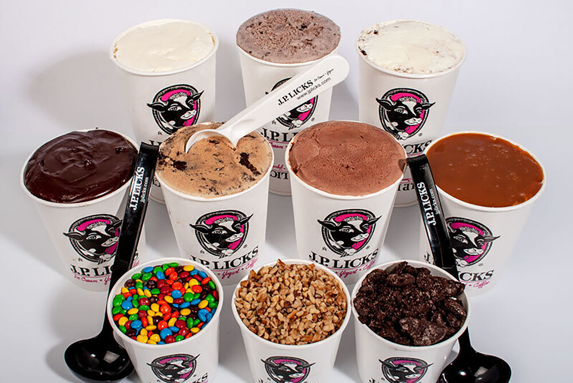 Photo: Ten different paper containers with the JP Licks logo sit on a white table. The ten different containers have different toppings and fillings for ice cream, showing JP Licks selection.