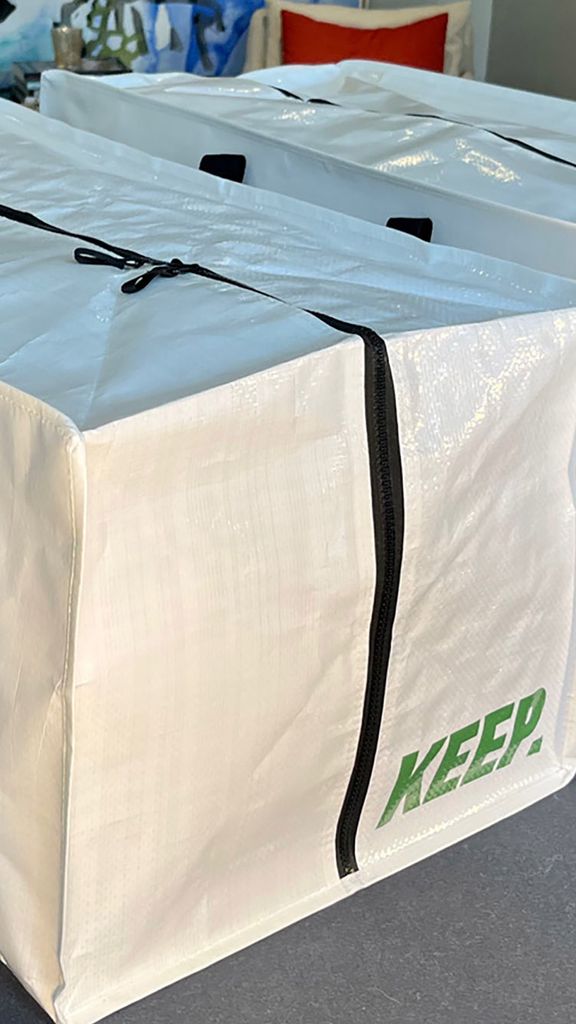 Photo: Two big, white plastic rectangular storage bags with black handles and green logo on the side that reads KEEP.