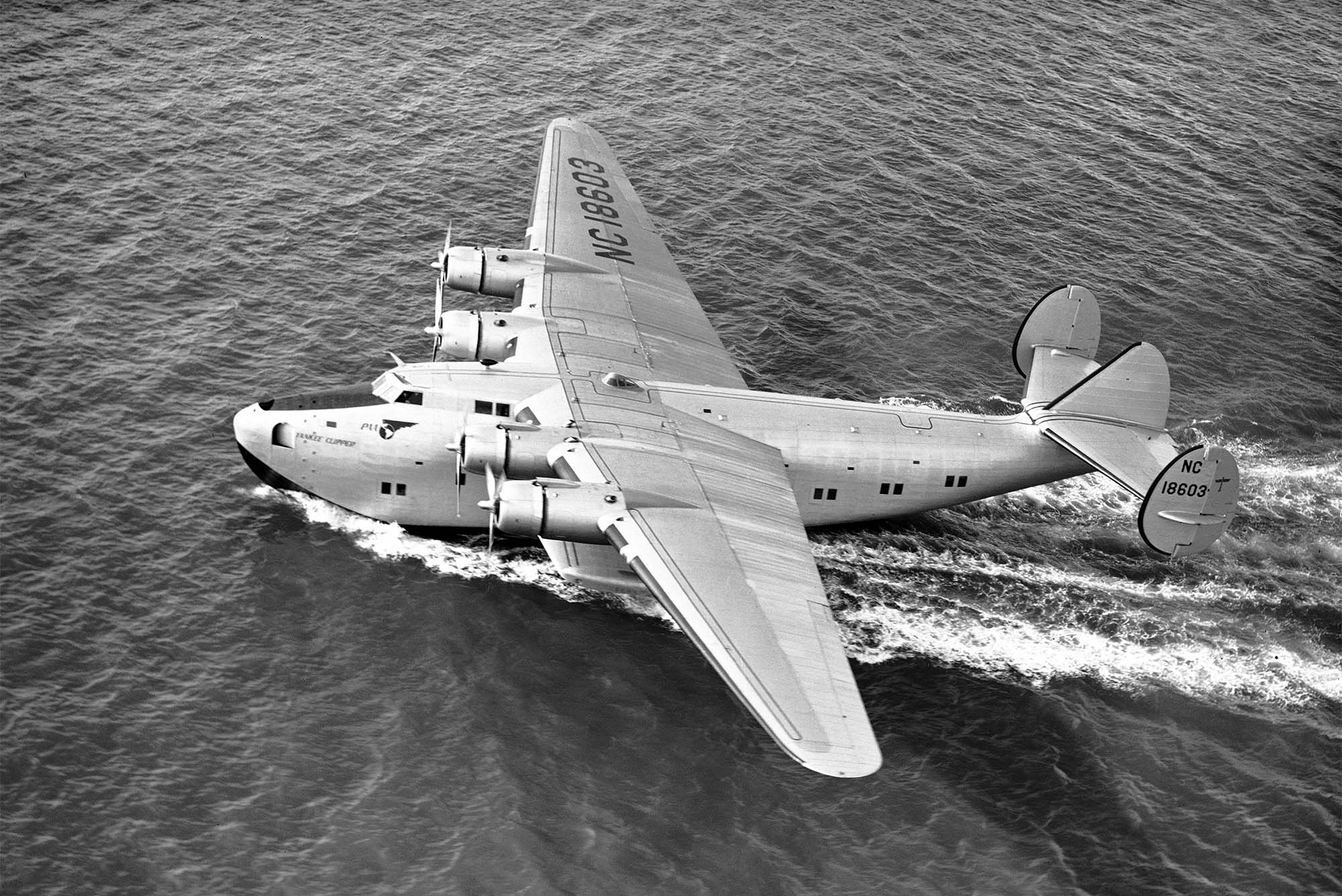 Photo: A large seaplane floating in a body of water. The photo is black and white and was taken a long time ago.