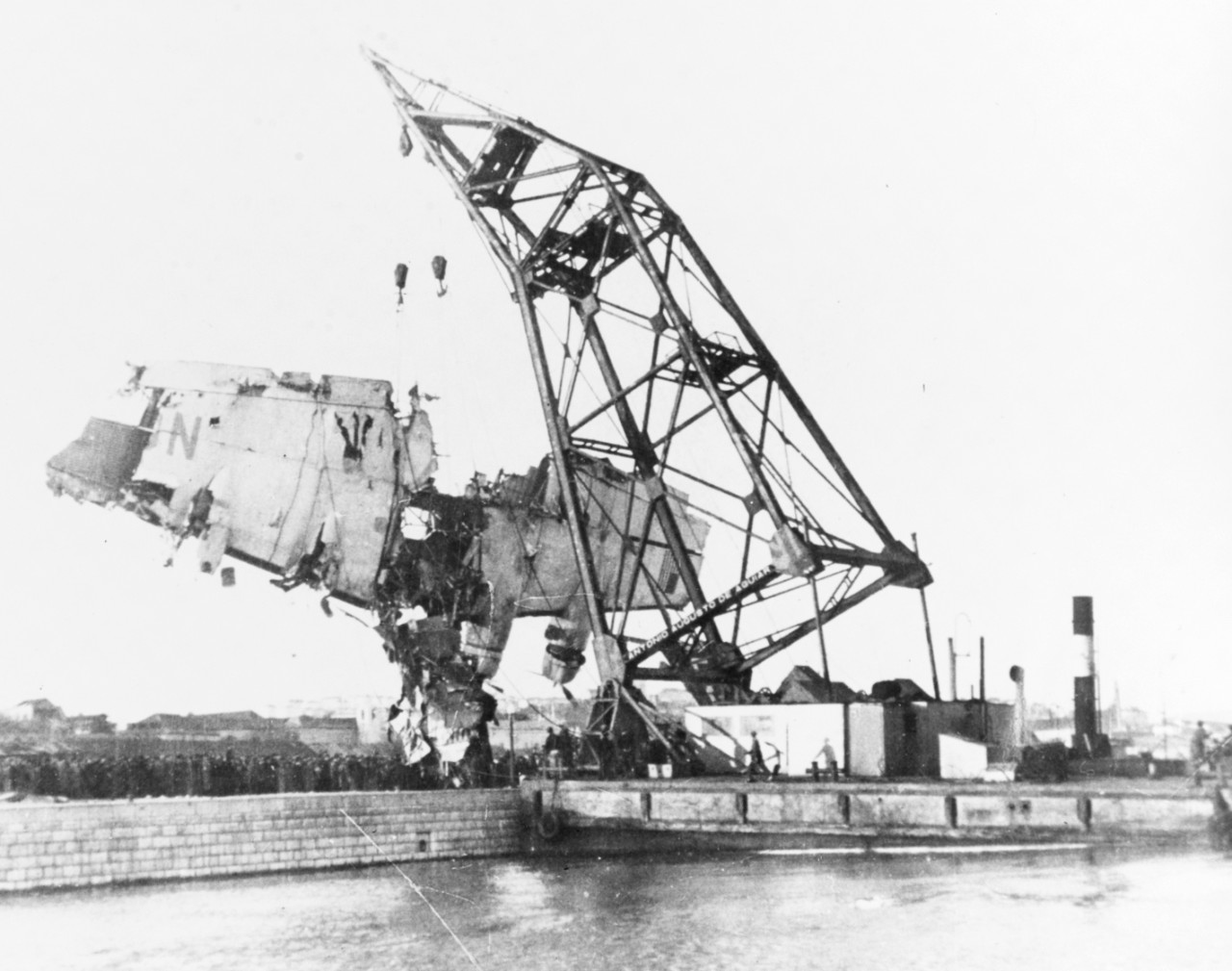 On 22 February 1943, floating crane places the plane's wreckage on a quai during salvage operations after the crash. The plane was a Boeing B-314A flying boat of Pan American Airlines.