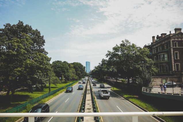 Photo: Image of Storrow Drive in Boston, MA. A two-lane local highway is shown with both directions of traffic on a sunny day. the Boston city skyline can be seen in the distance and Boston University buildings can be seen to the right.