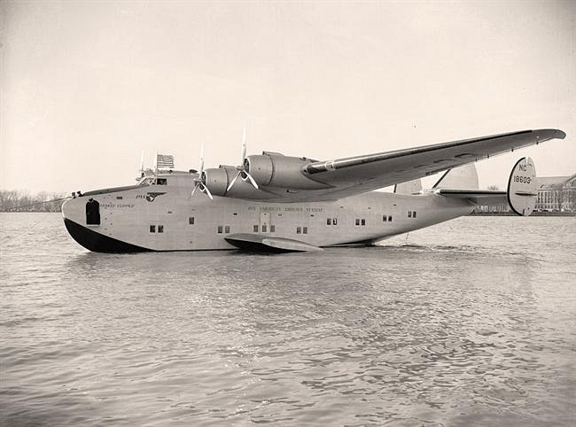 Photo: A large seaplane floating in a body of water. The photo is black and white and was taken a long time ago.
