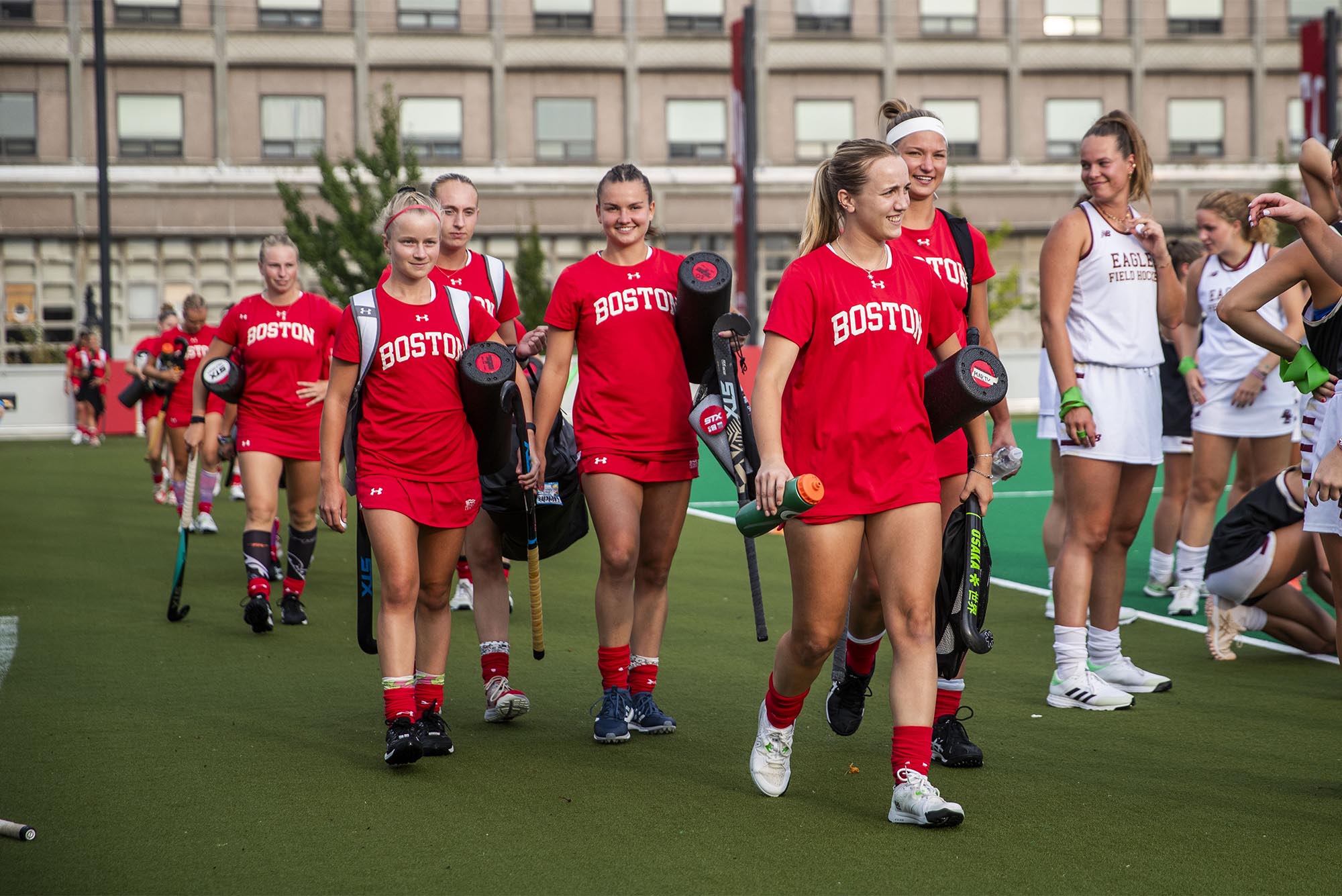 Photo: A group of women's field hockey players on Boston University's college team walk onto the pitch in red uniforms