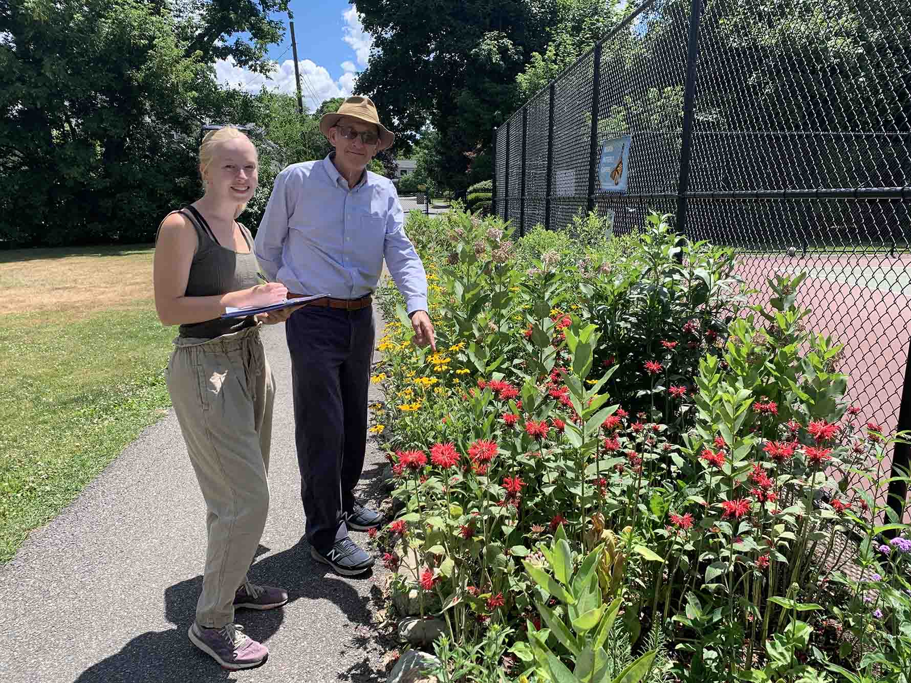 Photo: Selby Vaughn (left) and Richard Primack (right), wear summer outfits as they observe colorful pollinator plants on BU's campus.