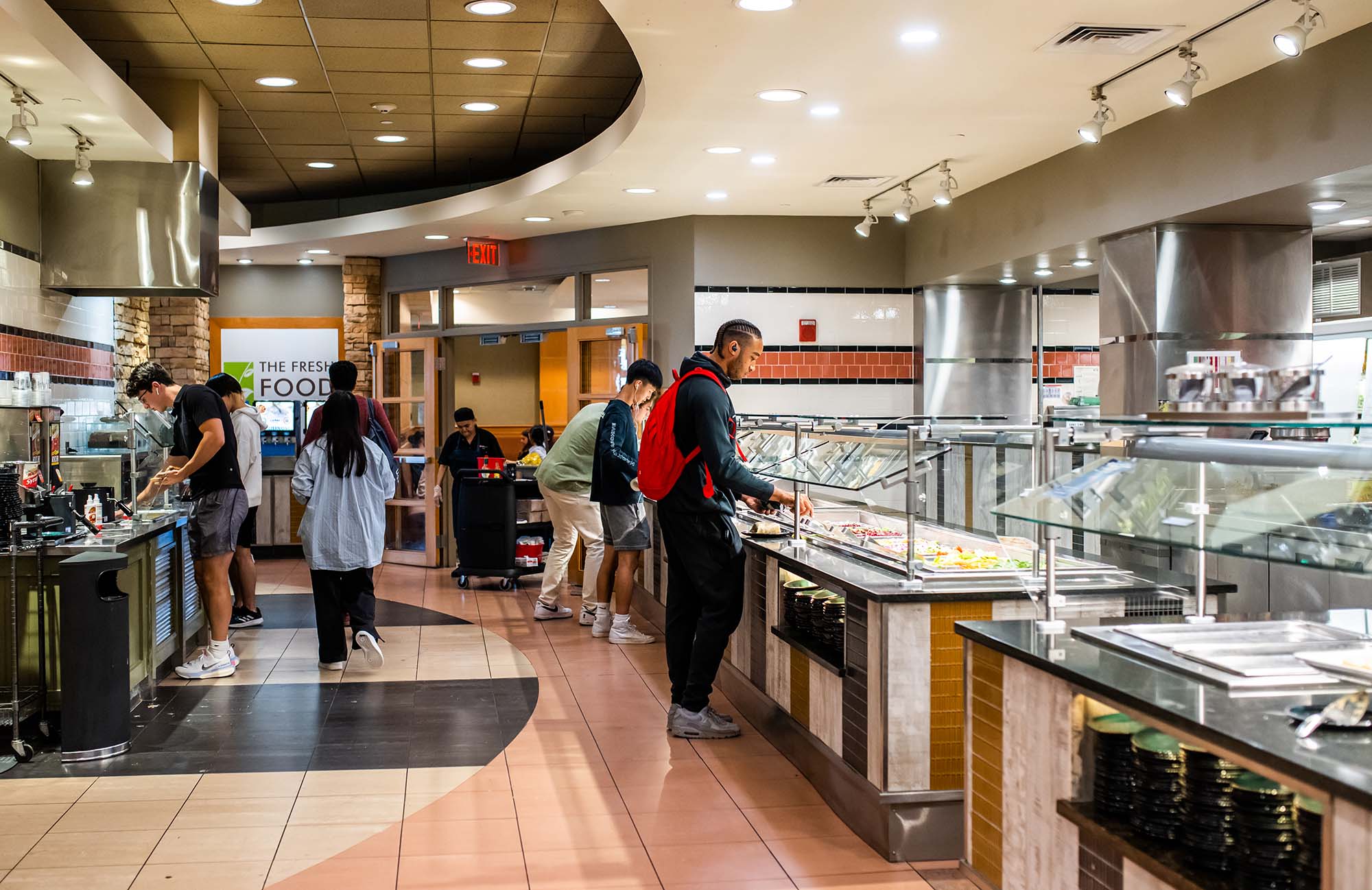 Photo: Students are shown sitting, eating, and getting food at the Fresh Food Co. dining hall in BU's West Campus.