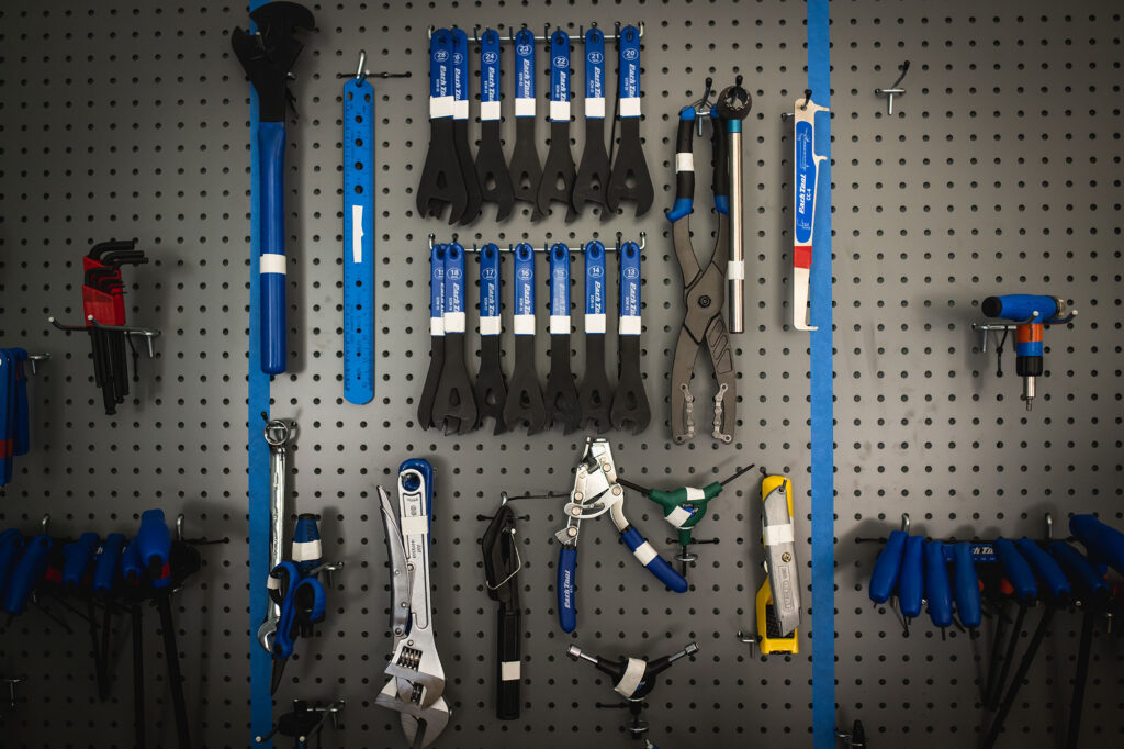 A large tool wall is shown. Bike tools are arranged carefully on the grey wall space.
