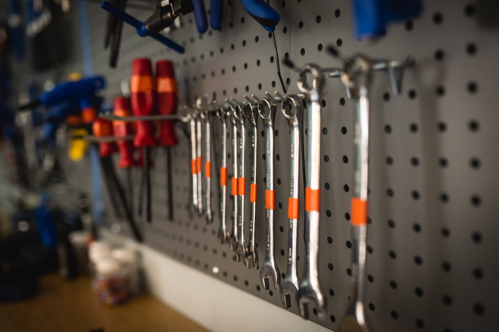 Photo: A row of bike wrenches in various sizes hang off a grey tool wall.