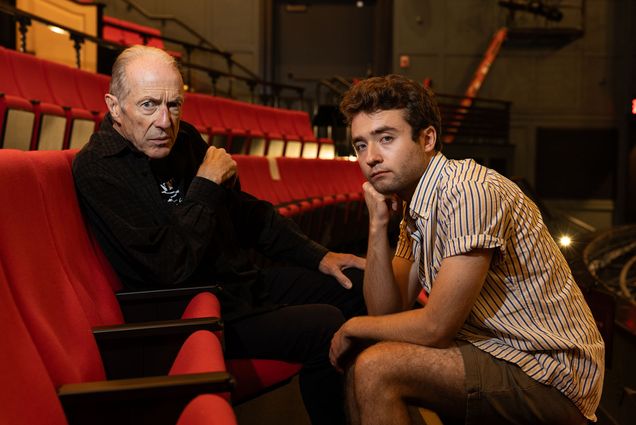 Photo: Will Lyman (CFA’71), an older white man, sits in the audience chairs as he looks at the camera with a side eye, posed strong. Jesse Kodama (CFA’25), a younger white man with short brown hair, sits across from him, holding his head in his hand.