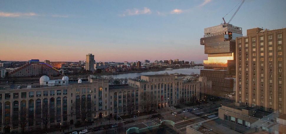 Photo of the Boston University campus, including the Center for data Science, from the top of the Photonics building. Campus view is seen during sunset, with orange and purple hues in the sky fading to a darkish blue.