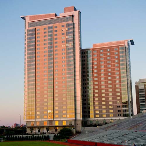 Photo of STUVII, a large dorm on BU's campus. The building is a light tan color and is seen at sunset.