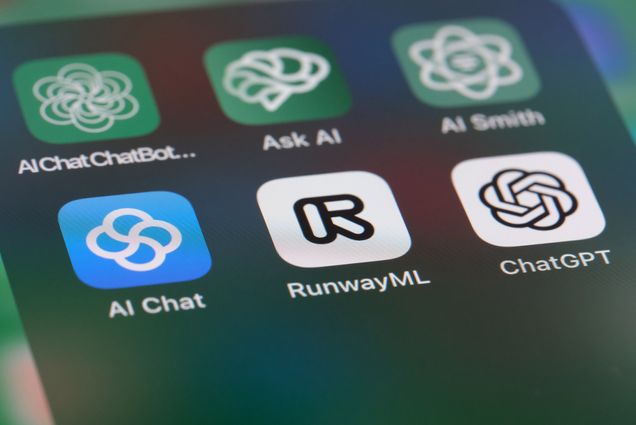 Image: A zoomed in photo of a phone screen showing icons for OpenAI ChatGPT and other AI application software.