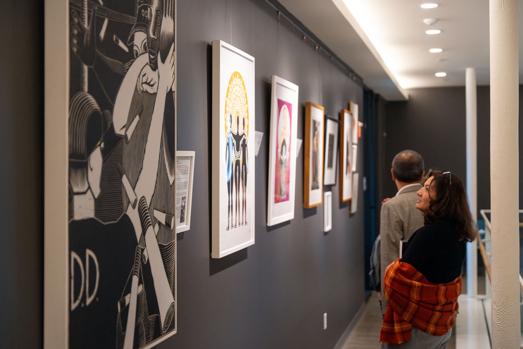 Photo: Patrons look towards the large artwork displayed on the dark walls of a gallery.