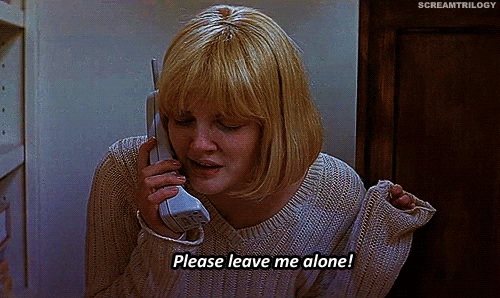 This is a GIF from the sixth Scream movie. The actress has a blonde, short, bob haircut and has pale skin. She's in a tan/pink-ish v-neck knit sweater. In one hand, she has a old-style white, cordless phone up to her ear. Her other arm is up by her shoulder and she is nervously fidgeting with the edges of her sweater. She is talking into the phone nervously with her eyes closed. There is a caption at the bottom of the GIF that says "Please leave me alone!" which mimics the words she is saying. 