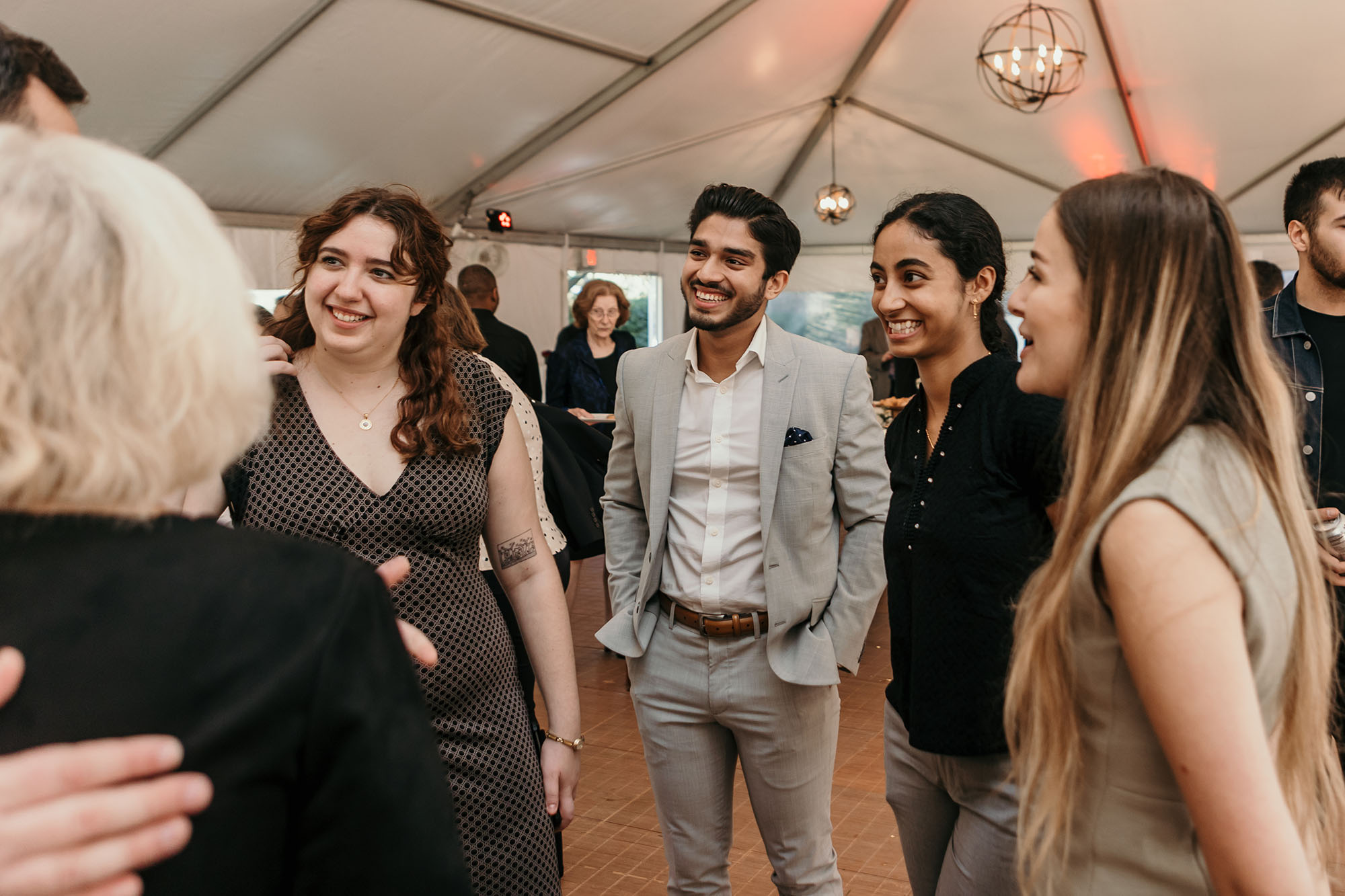 Photo: At the reception, Ilana Keusch (from left), chief justice of Student Government, Dhruv Kapadia, Student Government president, Navya Kotturu, Student Government executive vice president, and Hanna Dworkin, Student Government senate chair. A small group of young adults wearing business casual attire smile as they mingle at a reception.