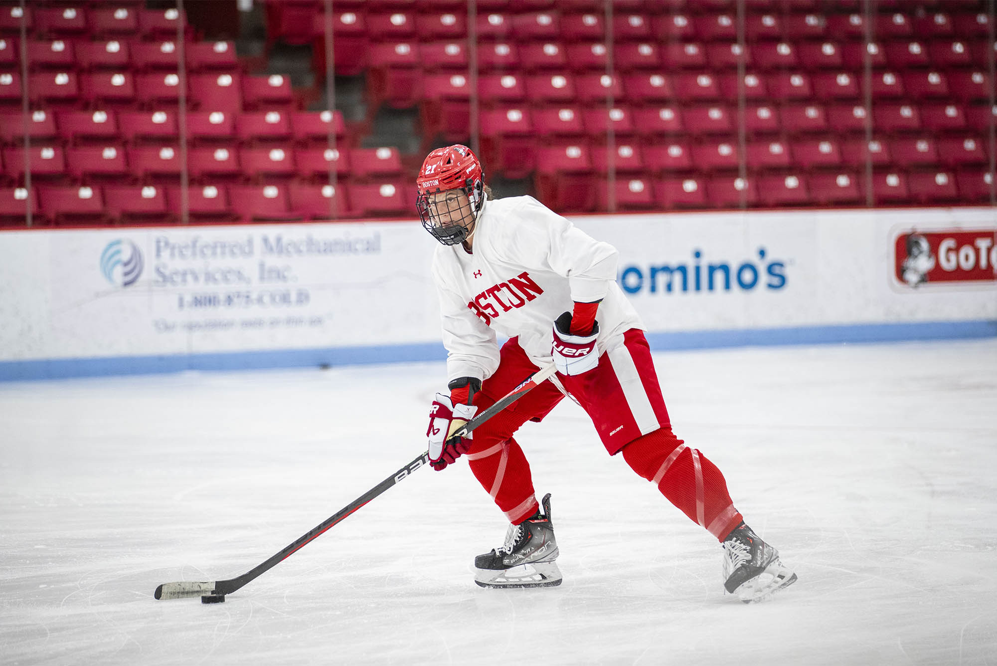 Photo: A hockey player in Boston University red and white uniform skating down ice with the puck