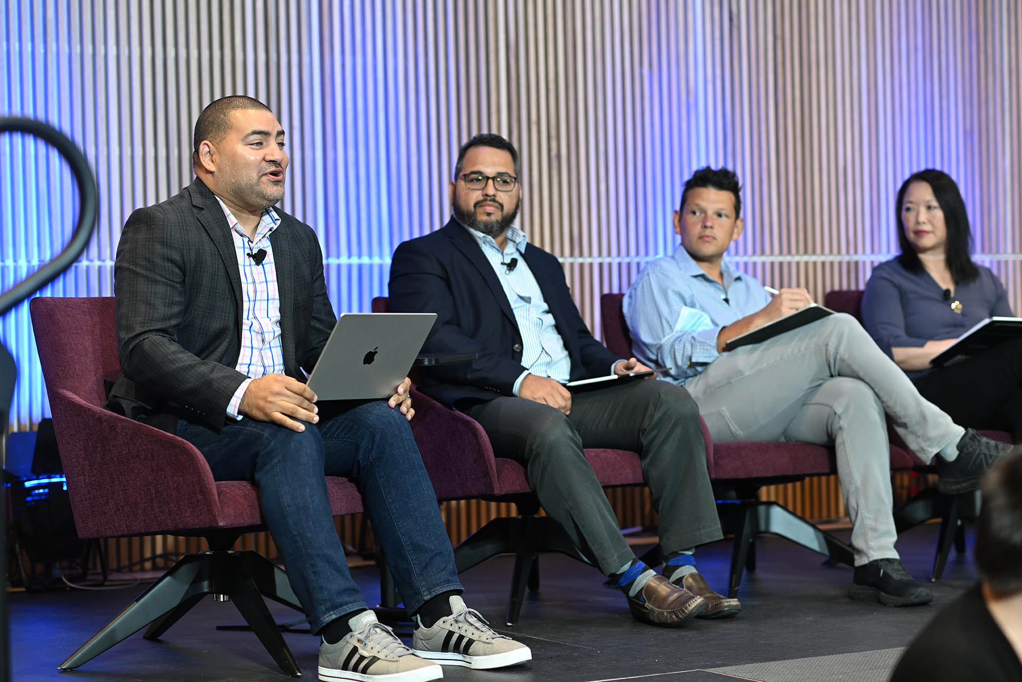 Photo: (Left to right) Dr. Raul Fernandez, moderates a panel discussion as Amin Abdul-Malik Gonzalez, Iván Espinoza-Madrigal, and Maria Dykema Erb look on. Four p[eople sit in burgundy arm chairs on a stage as they speak and interact with the seated audience in front of them.