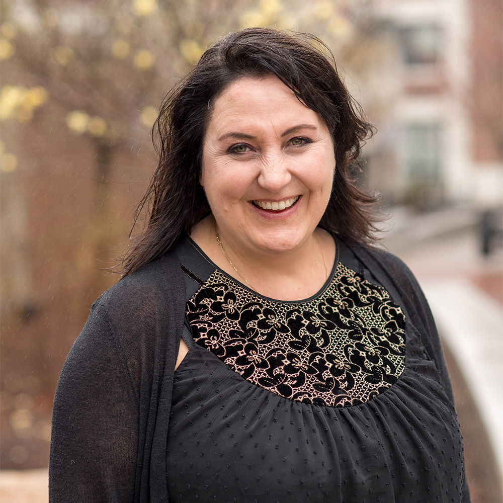 Photo: A woman with long dark hair smile joyfully in this outdoor headshot portrait