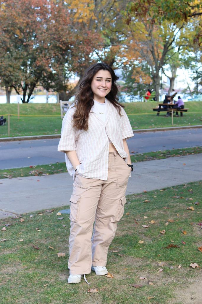 Photo: a student wearing a short sleeve dress shirt and cargo pants poses for a photo outside on a sunny day