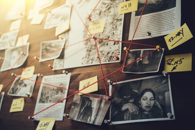 Photo: A stock photo of a cork board with red string connecting photos, cut outs, and stick notes.