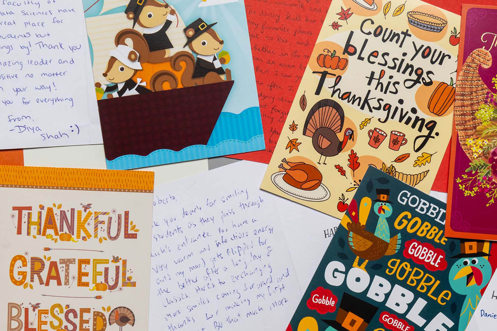 Photo: Overhead shot of a variety of Thanksgiving cards filled with heartfelt writing and notes are shown strewn out on a table.