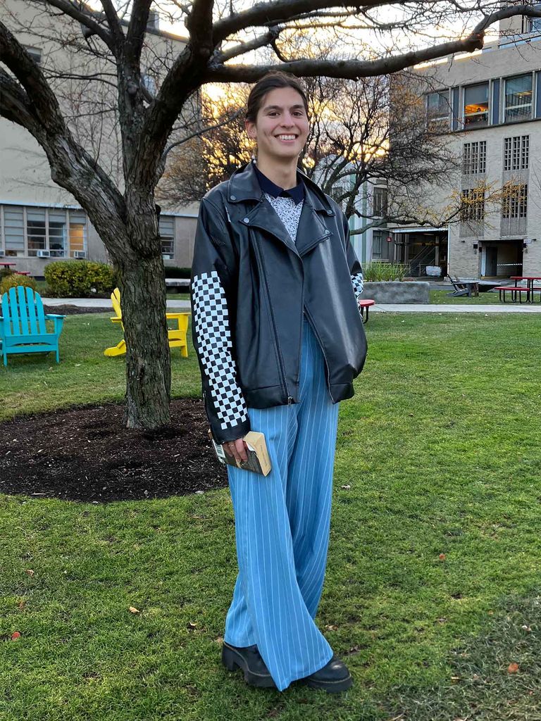Photo: A college student with short dark hair and a smile wearing blue pants and a leather jacket