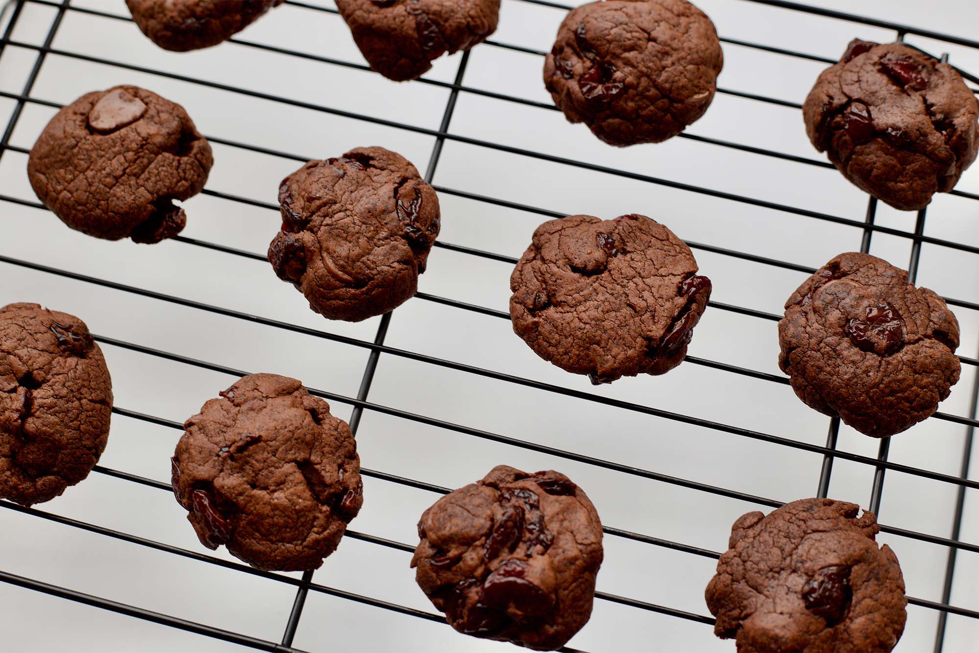 Photo: A tray of cookies on a wire baking rack. They have cherries and chocolate chips