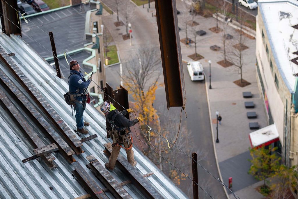 Photo of two construction workers watching as a beam is lifted off the data sciences center.
