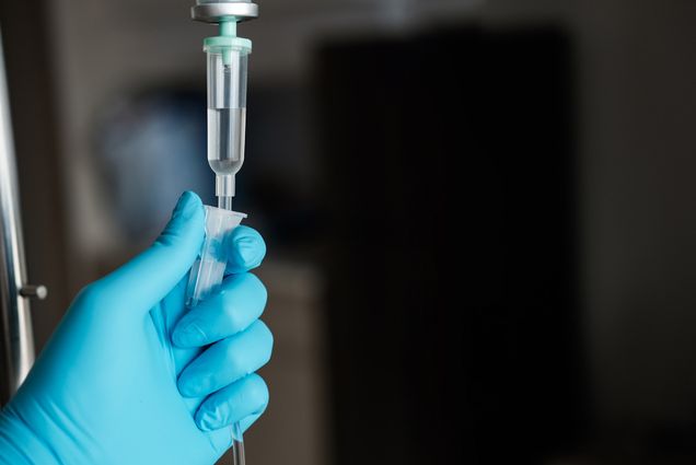 Photo: Doctor with gloved hand holds IV for chemotherapy treatment.