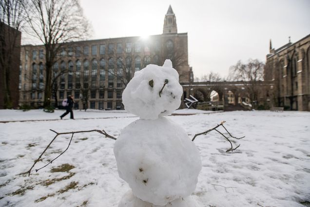 Photo: a snowman with stick arms and a hat on BU's campus on a cold winter day