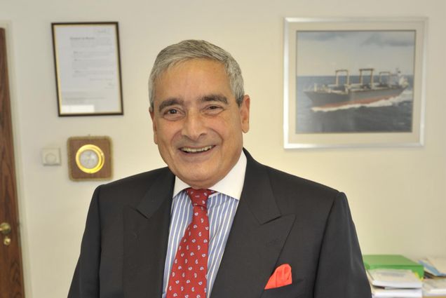 Photo: A man with a smile in a suit and tie in an office setting