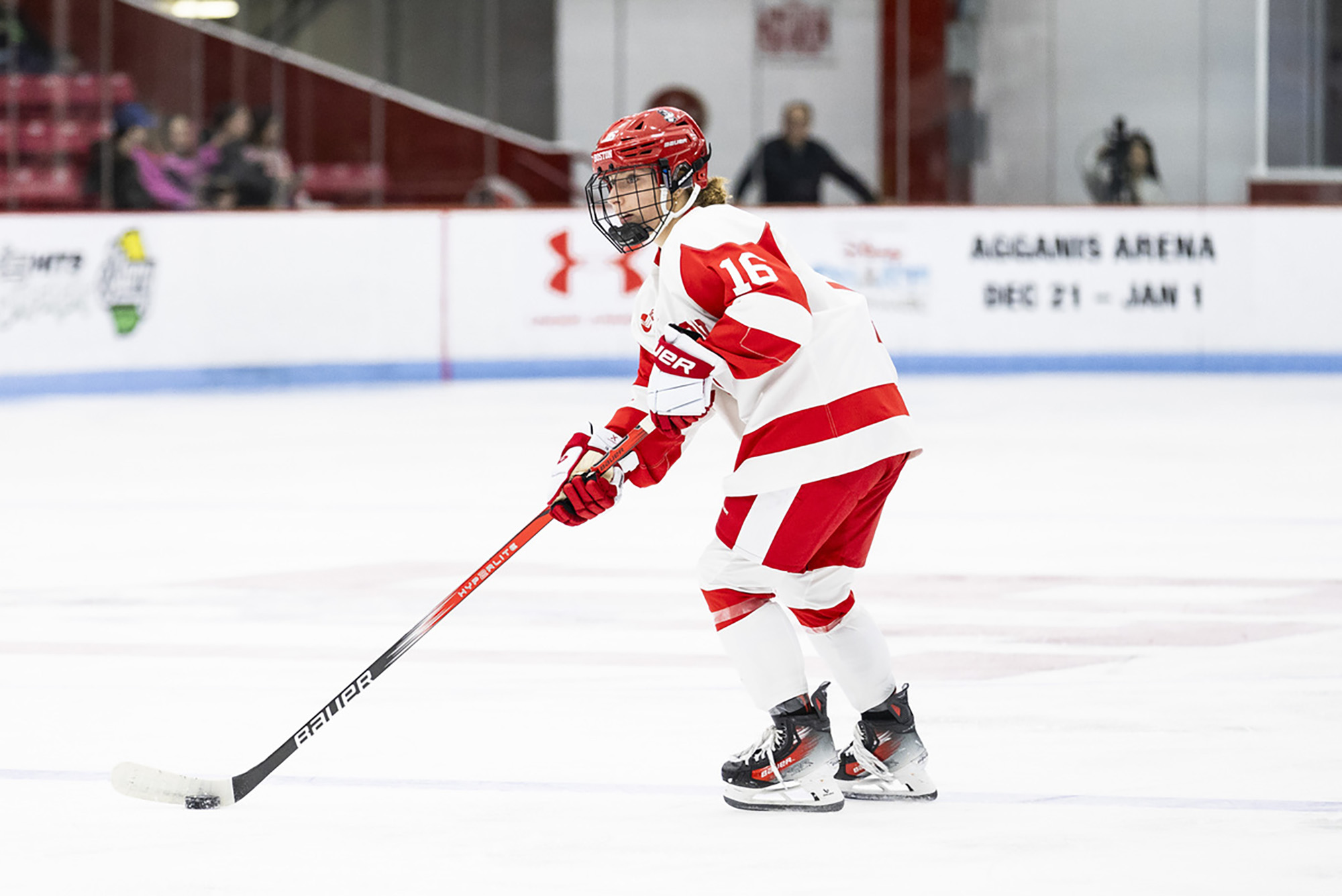 Photo: Luisa, a BU women's hockey player, skates with the puck in her BU uniform--white with red detailing and numbers.