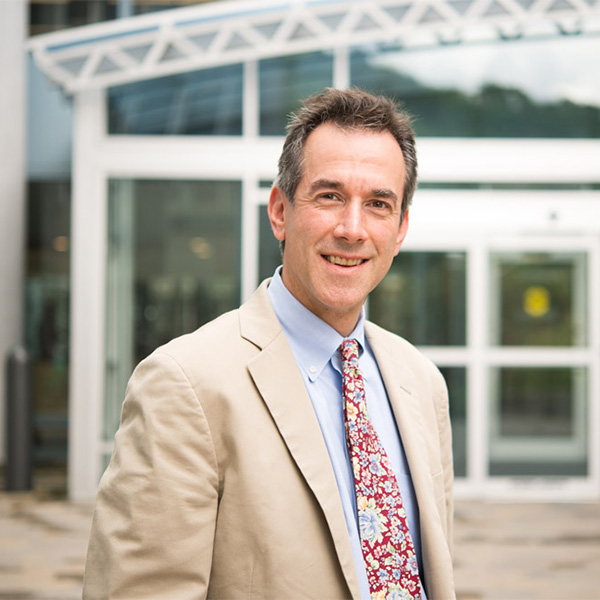 Photo: A well dressed man in a tan suit stands in front of a modern building in this posed portrait