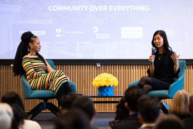 Photo: Michelle Wu, the mayor of Boston, sits with Jeneé Osterheldt, a black woman who is the Culture Columnist and Deputy Managing Editor at the Boston Globe at the Civic Center Summit. They sit across of each other on the panel with a screen behind them.