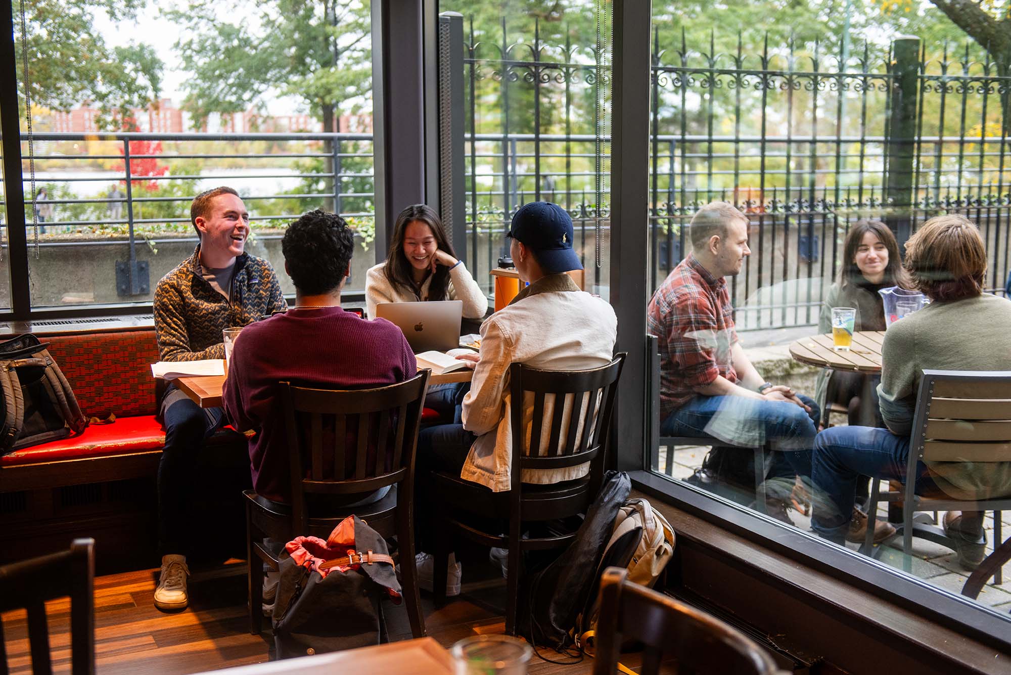 Photo: A group of friends sit at a table and eat, chat, and laugh.
