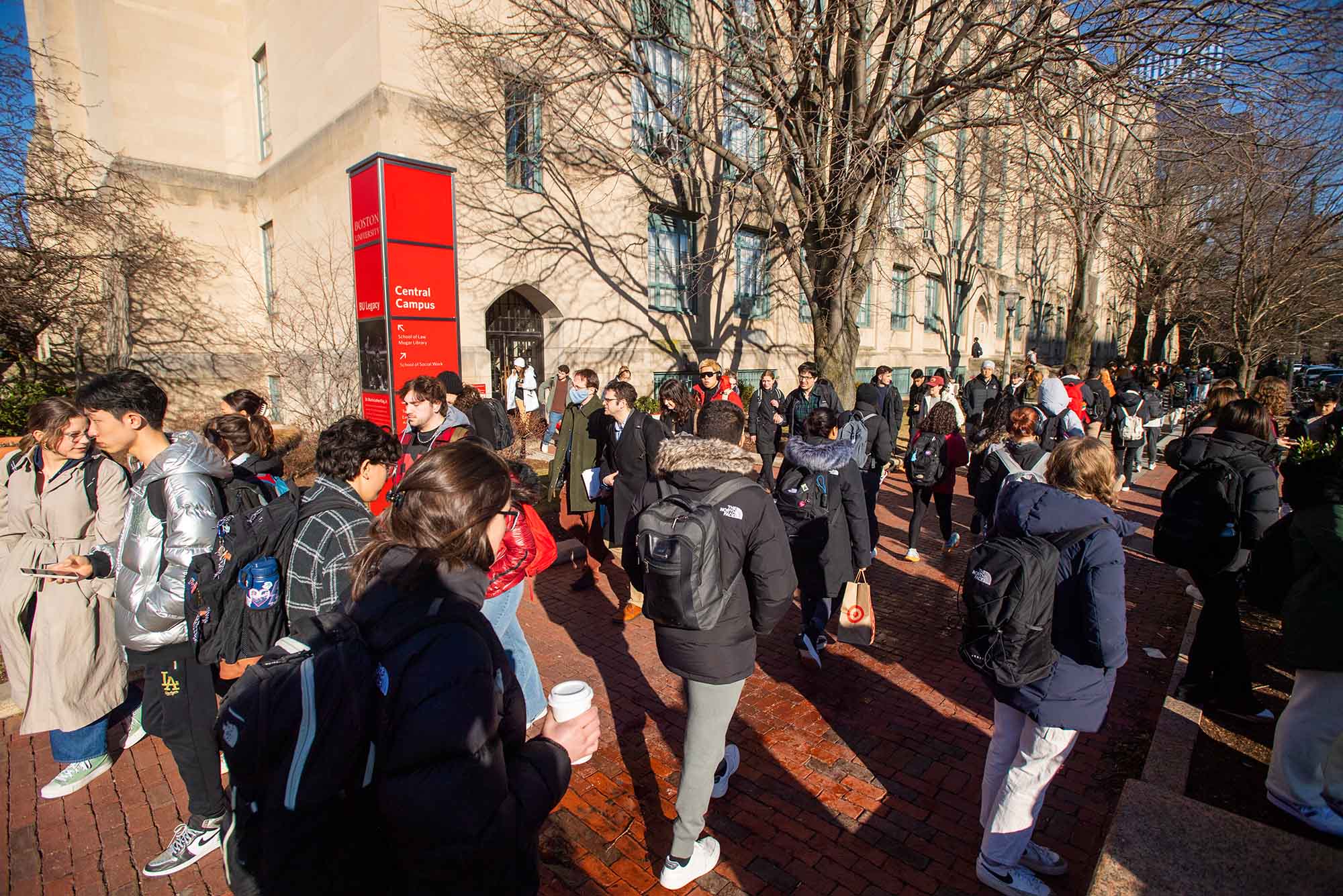 Photo: A crowd of students mingle and commute to their classes on Bu's campus. Various different coats and backups adorn them.